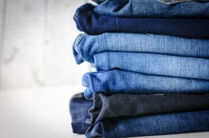 Image shows a pile of jeans of various shades of blue.