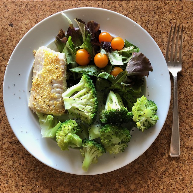 Image shows a plate of food containing a salad, fish and broccoli.